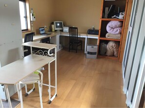 Une petite pièce comprenant un bureau, deux chaises, un ordinateur et un radiateur.