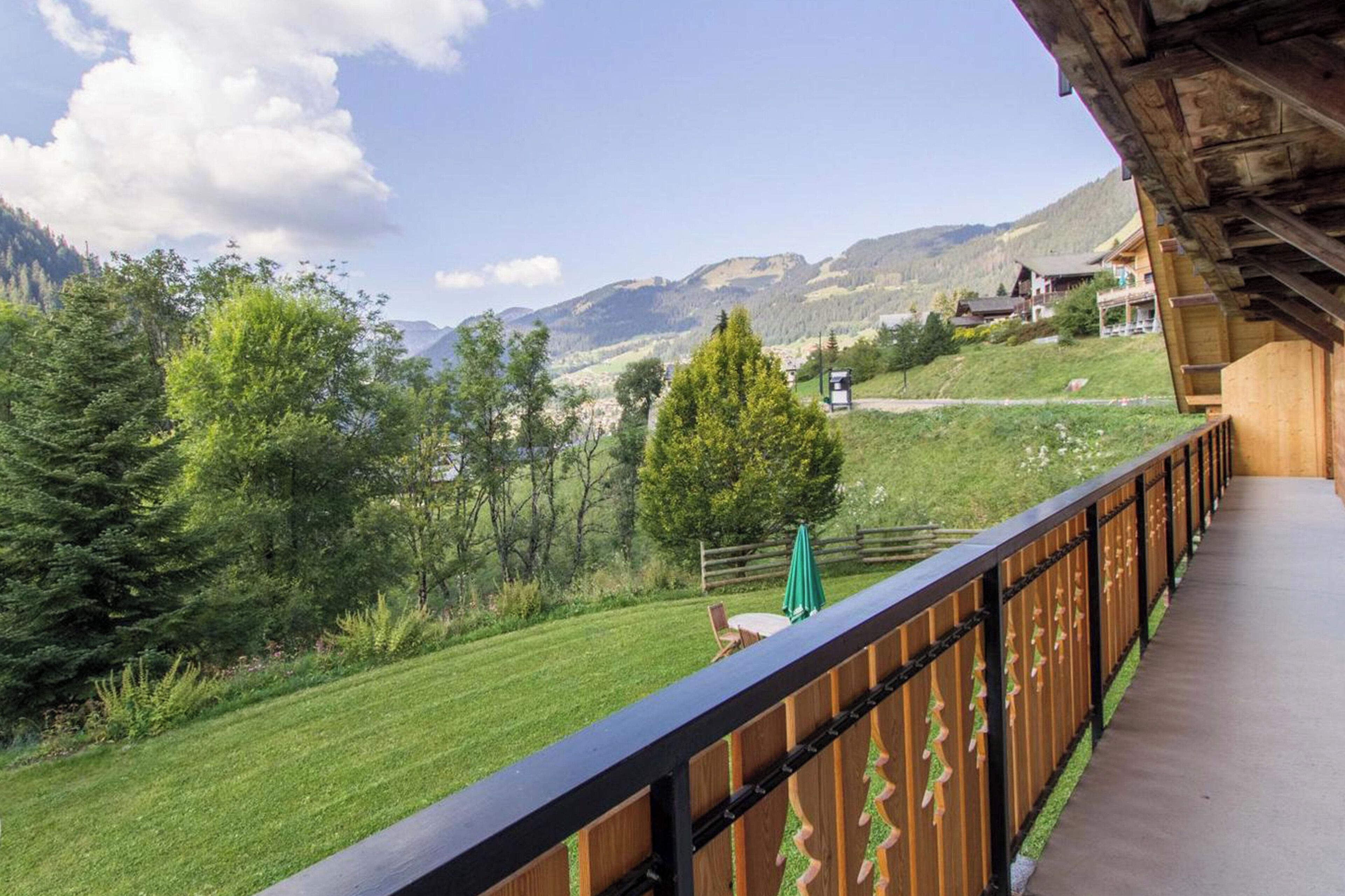 Un balcon donnant sur un paysage verdoyant et des montagnes.