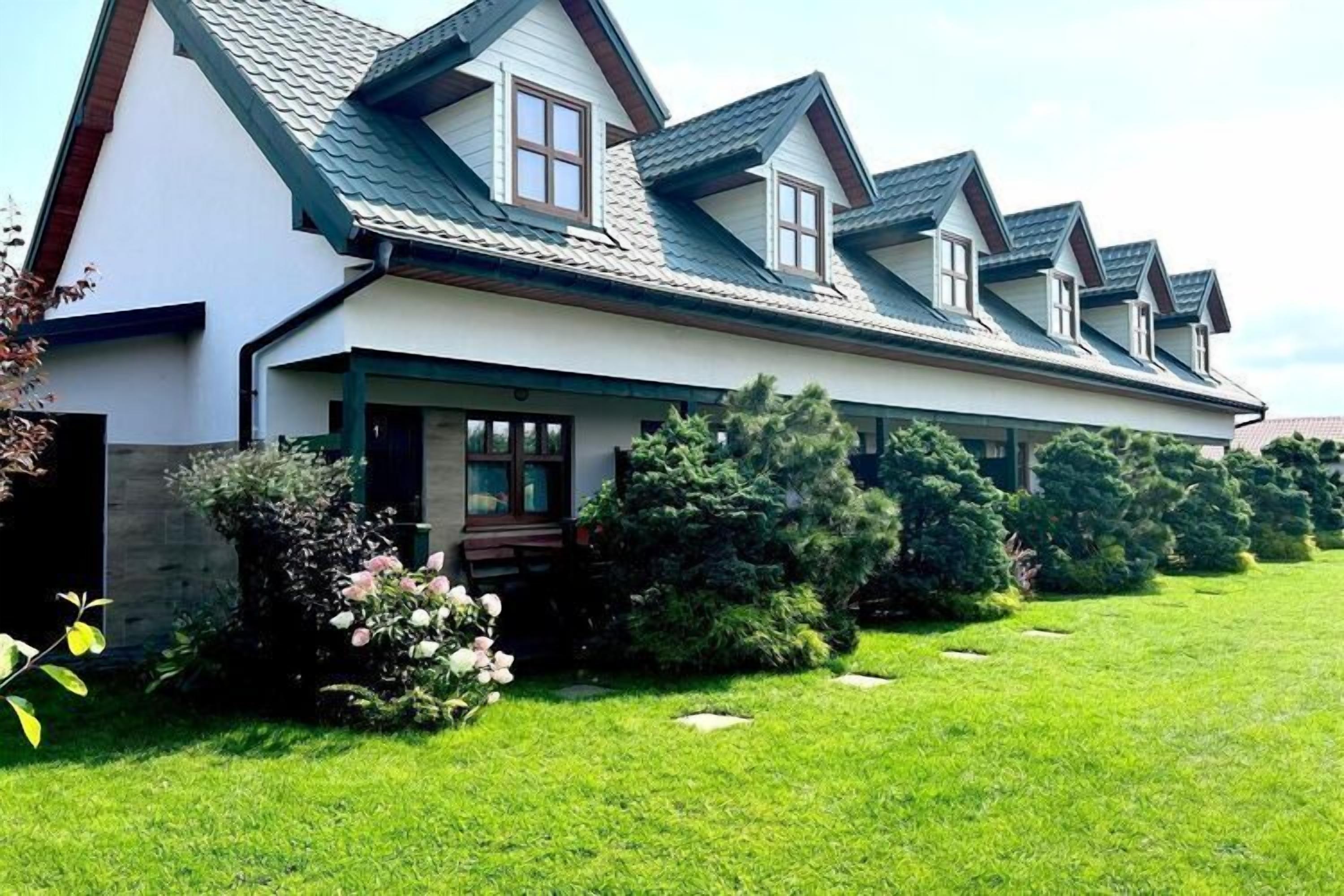 A two-story house with a sloped roof, a covered porch, and a well-maintained lawn.