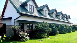 Ein zweistöckiges Haus mit geneigtem Dach, einer Veranda und einem gepflegten Rasen.
