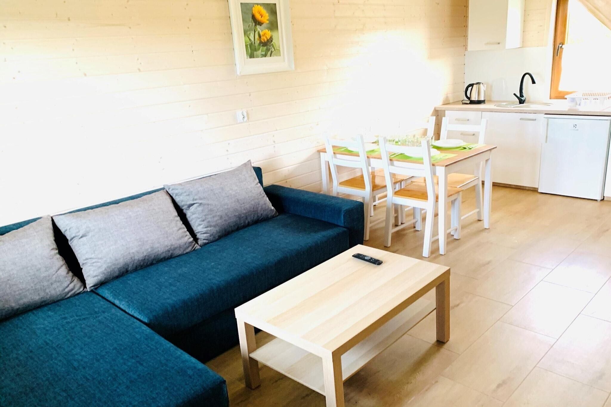 A living room with a blue sofa, a wooden coffee table, and a dining area with white chairs and a table.