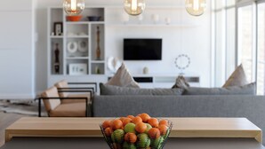 Una sala moderna con una mesa de centro de madera, un cuenco de frutas y un sofá gris.