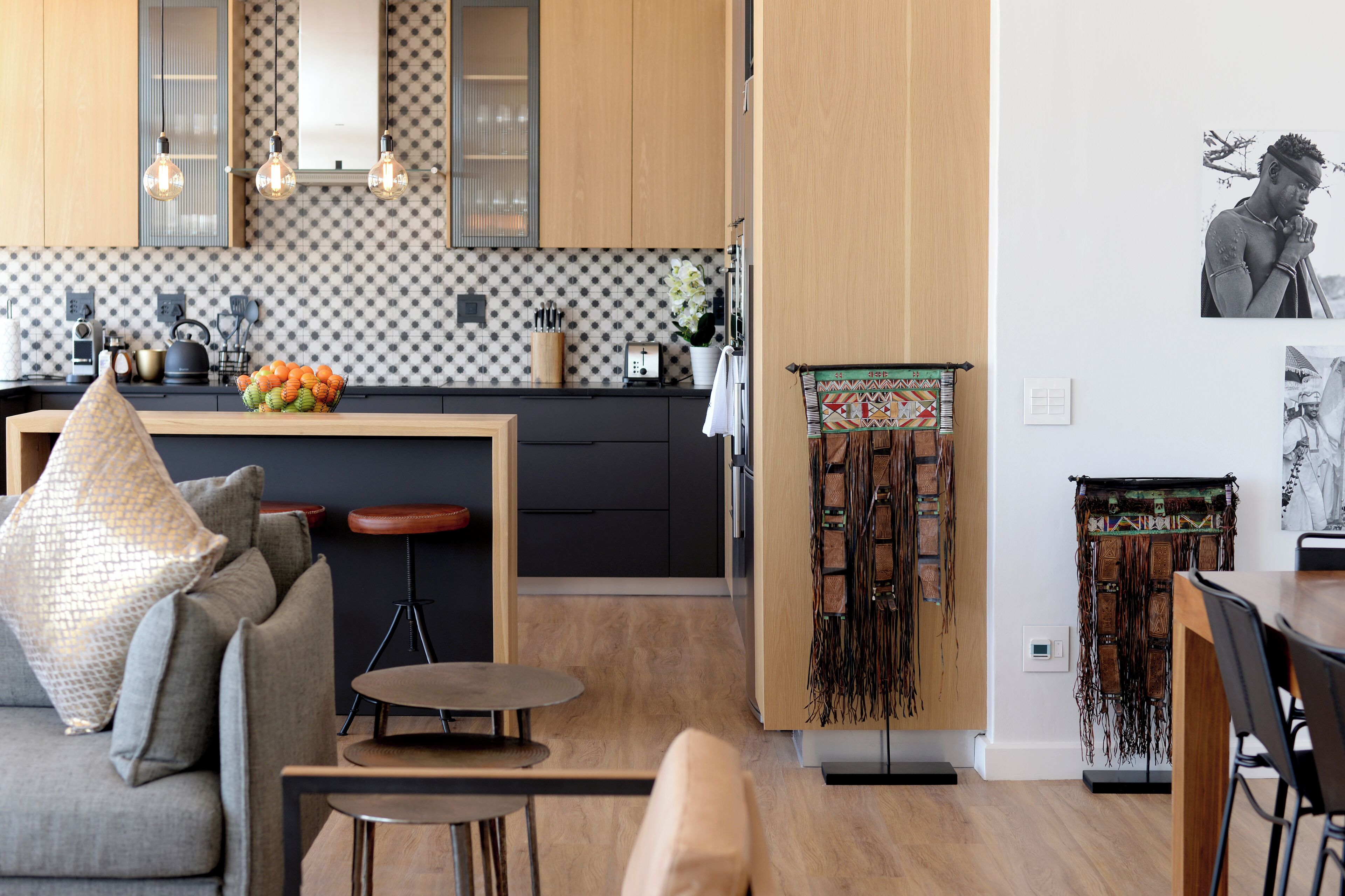 Una cocina moderna con una isla central, armarios de madera y un salpicadero con estampado.
