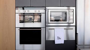A kitchen with a built-in oven, microwave, and a stainless steel refrigerator.
