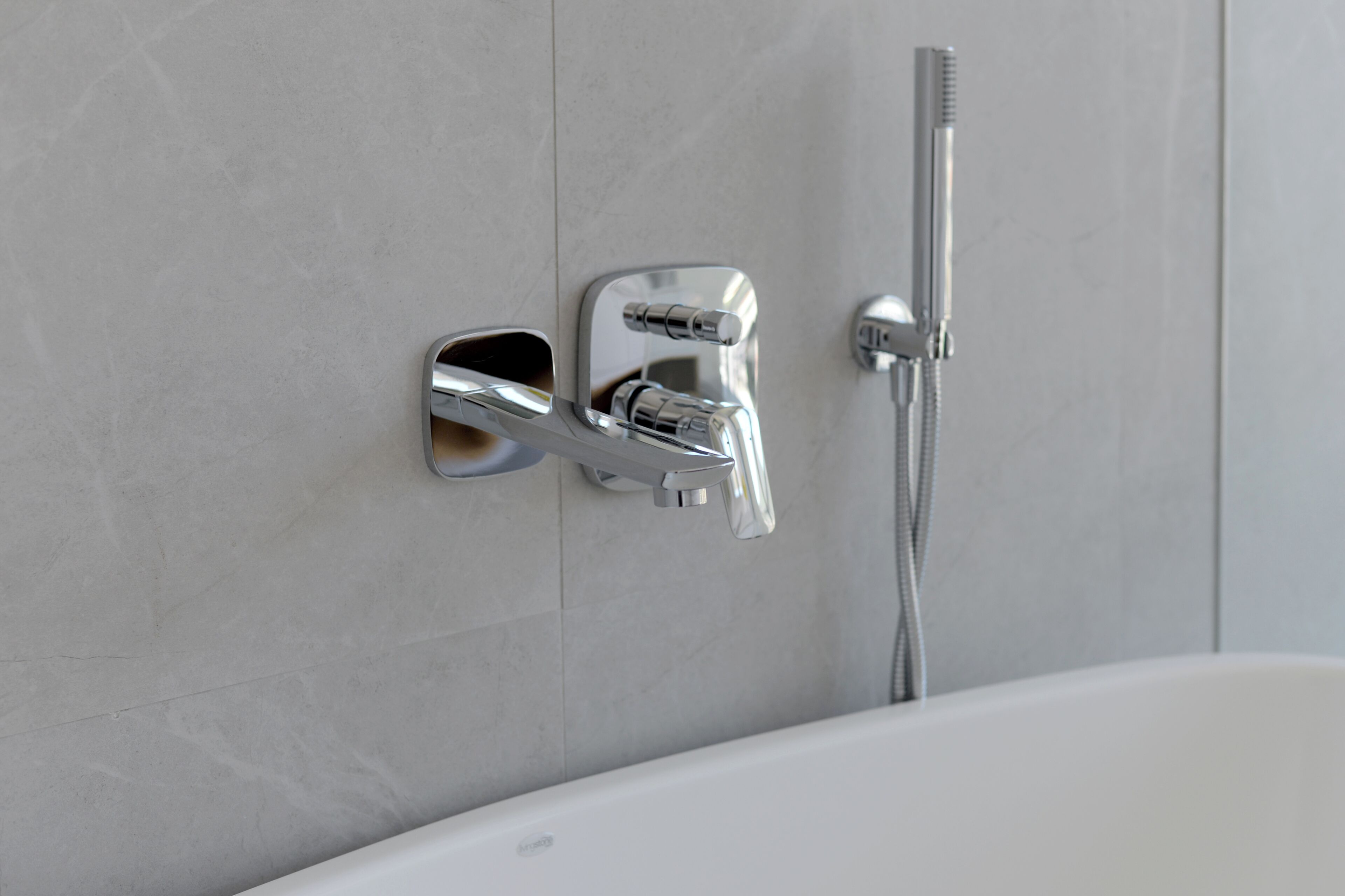 Une salle de bain moderne avec un robinet chromé, une douchette et une baignoire blanche.
