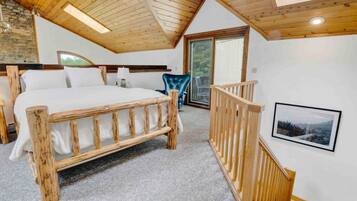 Une chambre avec un lit en bois, une chaise bleue, un escalier en bois et un tableau encadré au mur.