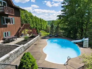 A backyard with a swimming pool, a deck, and a slide. - Poolside Paradise on Plum Creek (Ellicottville)
