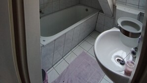 Ein Badezimmer mit einer Badewanne, einem Waschbecken und einem Fenster.