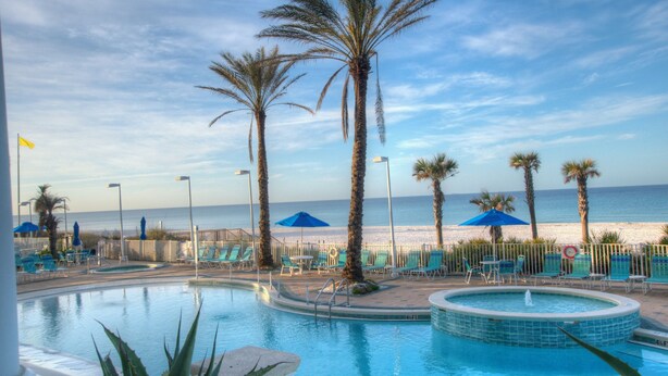 A pool area with lounge chairs and umbrellas, palm trees, and a view of the beach and ocean. - Fantastic Gulf-front 1 Bd Condo At Boardwalk in Panama City Beach! (Panama City Beach)
