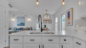 A modern kitchen with white cabinetry, a central island, and pendant lighting. - Fully Updated Beach Retreat; Minutes to Eastern Lake & Beaches (Santa Rosa Beach)