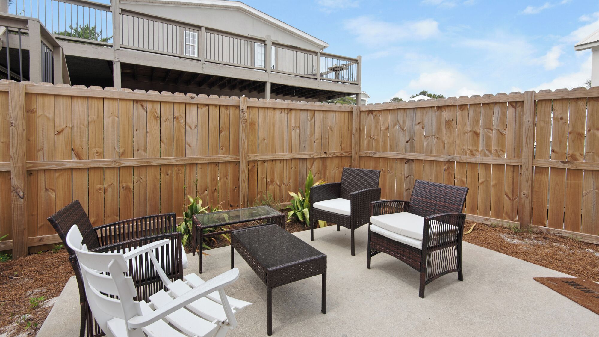A patio with outdoor furniture, including chairs and a table, set against a wooden fence.
