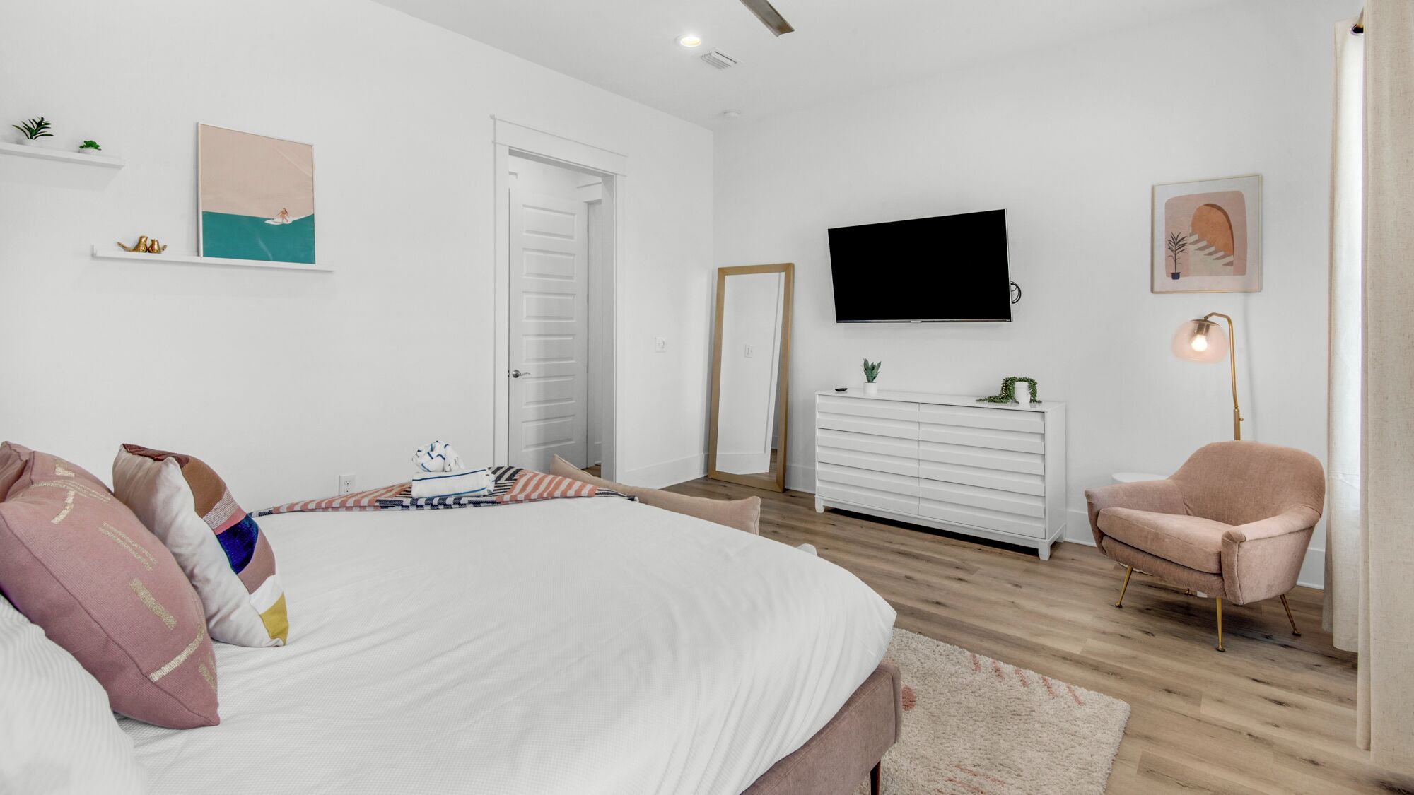 Un dormitorio con cama, cómoda, silla, televisor y puerta.