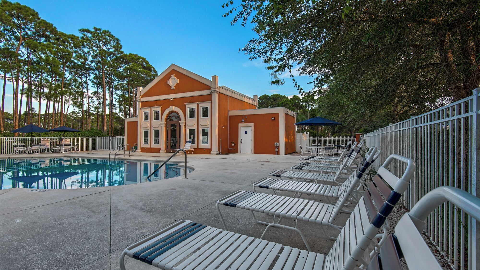 A pool area with lounge chairs and a building with a distinctive arched entrance.
