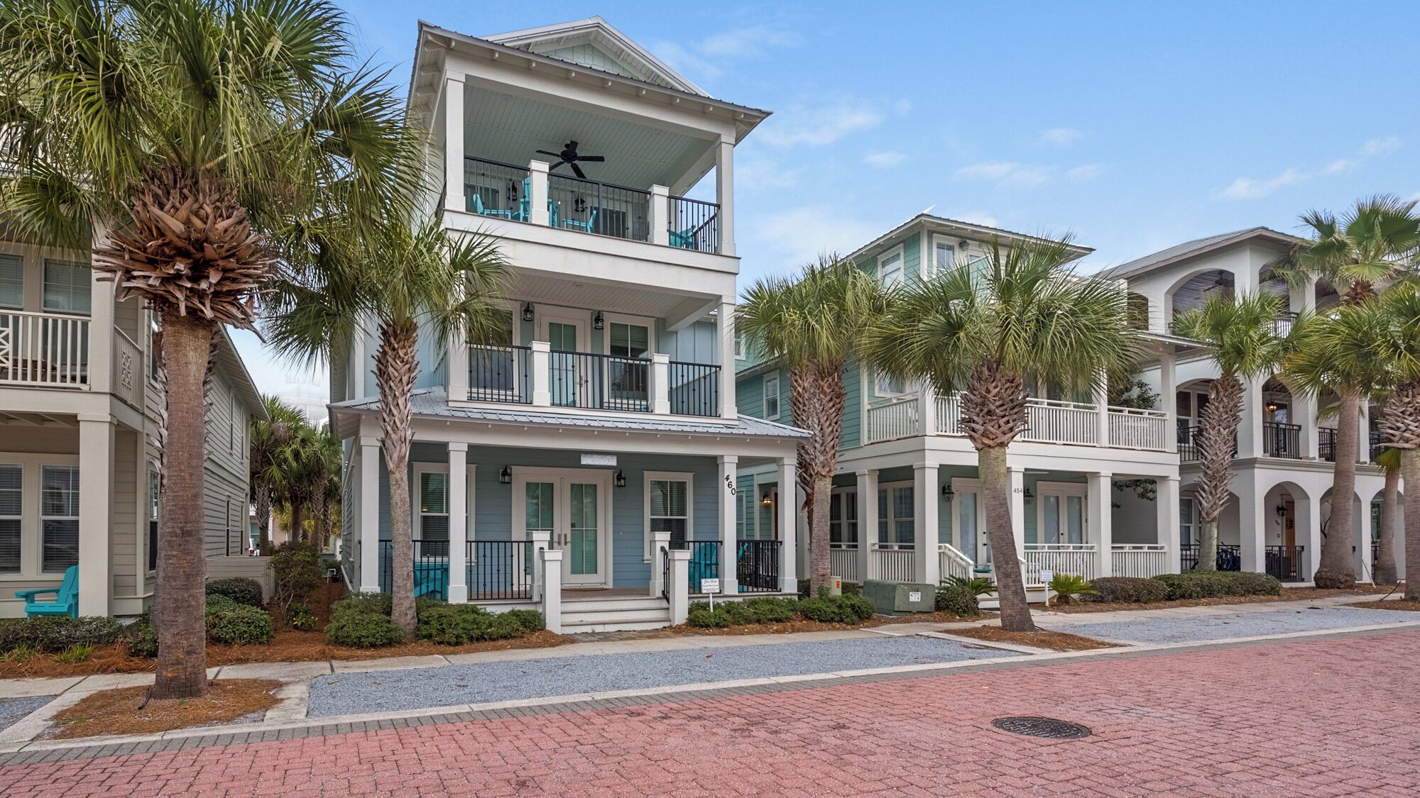 A multi-story hotel with balconies, palm trees, and a brick-paved walkway.