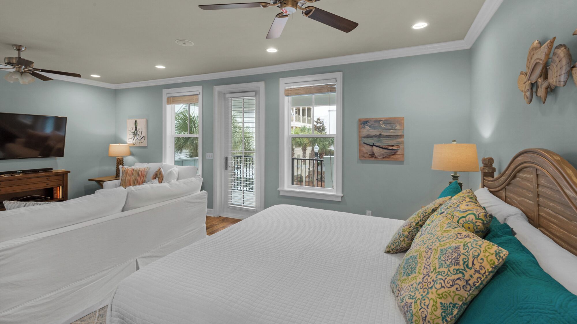 A bedroom with a large bed, a TV, and a ceiling fan.