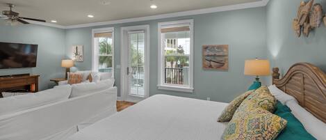 A bedroom with a large bed, a TV, and a ceiling fan.