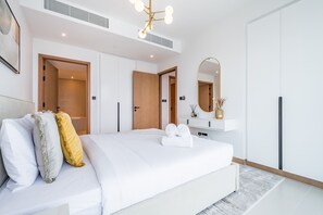 A modern bedroom with a large bed, a bedside table with a mirror, and a ceiling light fixture. - Delightful 2BR Apartment in VIDA Residences Dubai Marina by Deluxe Holiday Homes (Dubai)
