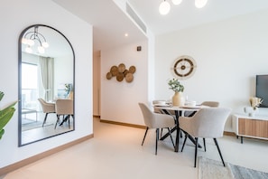 Un comedor moderno con una mesa redonda, sillas, un espejo grande y un reloj de pared.