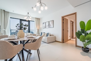 Una sala moderna con comedor, ventanas amplias y vista a la ciudad.