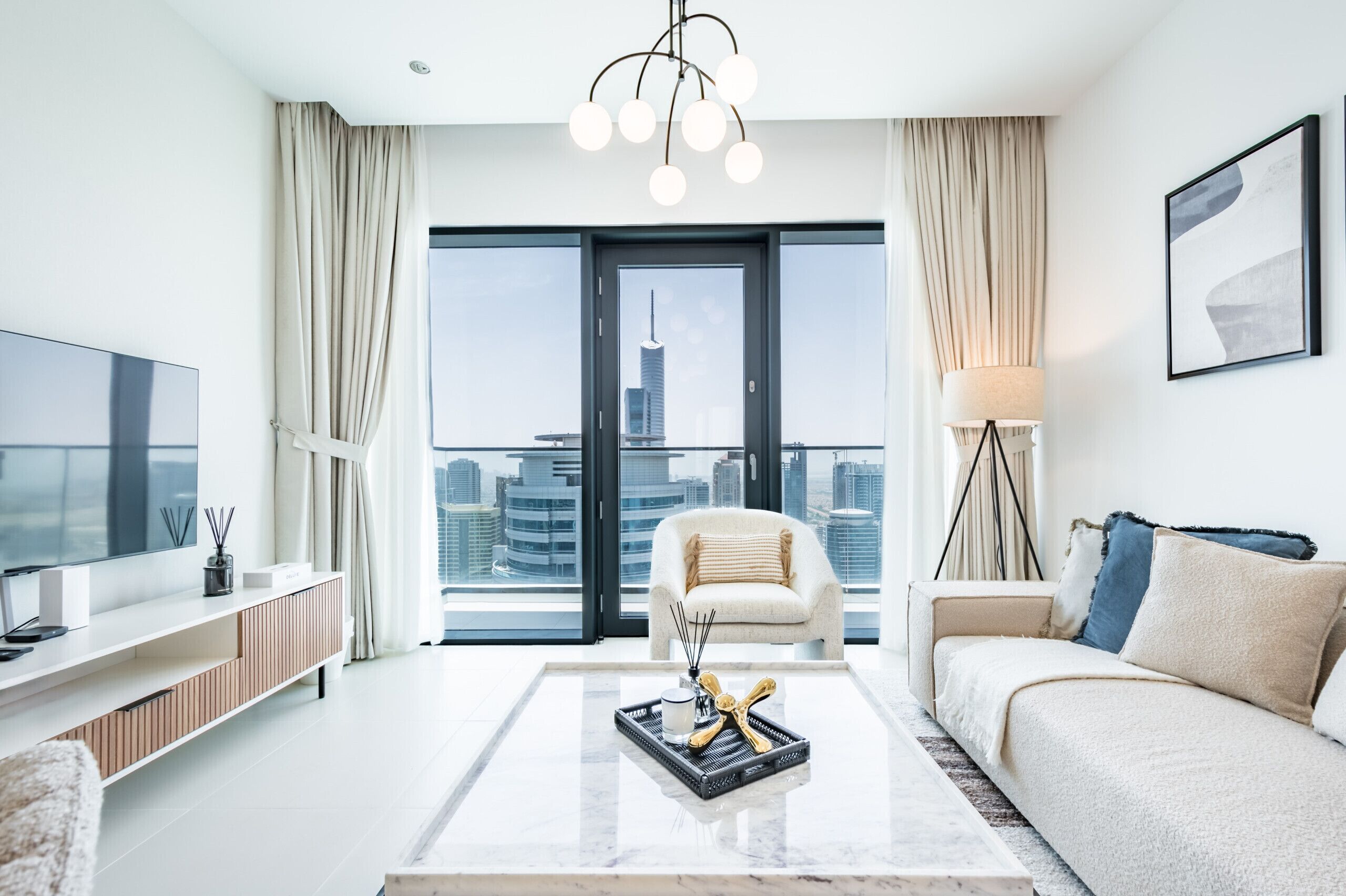 A modern living room with a large window, a sofa, a coffee table, and a TV.