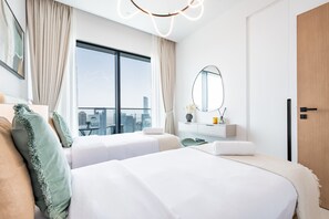 A hotel room with two beds, a large window with a city view, a mirror, and a wooden door.