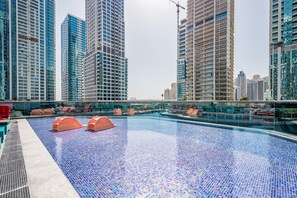 Ein Pool auf dem Dach mit einem Mosaikboden, umgeben von Hochhäusern.