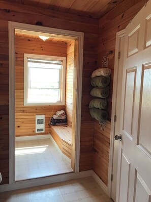A wooden cabin room with a small window, a door, and a wall-mounted towel rack.