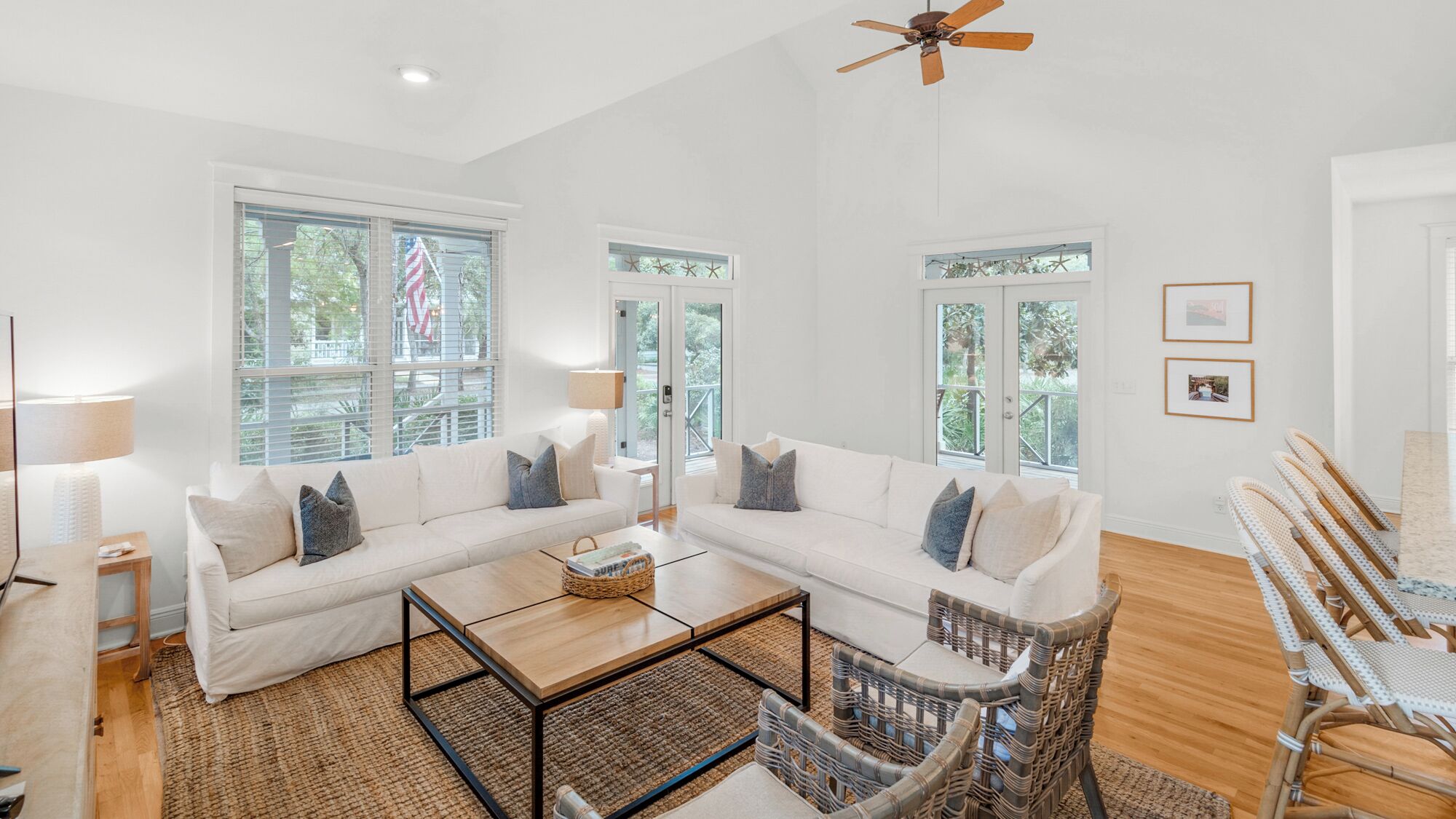 A spacious living room with a white sofa set, a coffee table, and wicker chairs.
