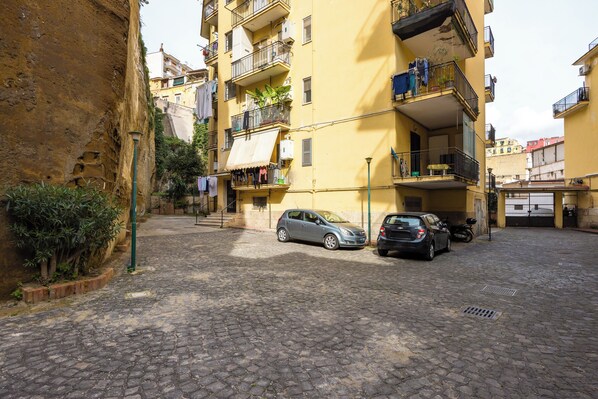 Una estrecha calle empedrada flanqueada por edificios amarillos de varios pisos con balcones, algunos con ropa tendida.