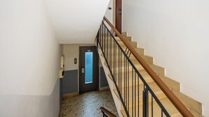 A staircase with a wooden handrail and black balusters, leading to a door with a frosted glass panel. - Montesanto View Rooms by Wonderful Italy (Naples)