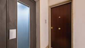 A hallway with a frosted glass door on the left and a wooden door on the right. - Montesanto View Rooms by Wonderful Italy (Naples)