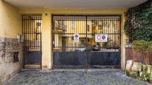 A gated entrance with a cobblestone path leading to a building with a yellow facade and barred gate. - Montesanto View Rooms by Wonderful Italy (Naples)