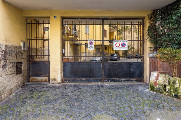 A gated entrance with a cobblestone path leading to a building with a yellow facade and barred gate. - Montesanto View Rooms by Wonderful Italy (Naples)