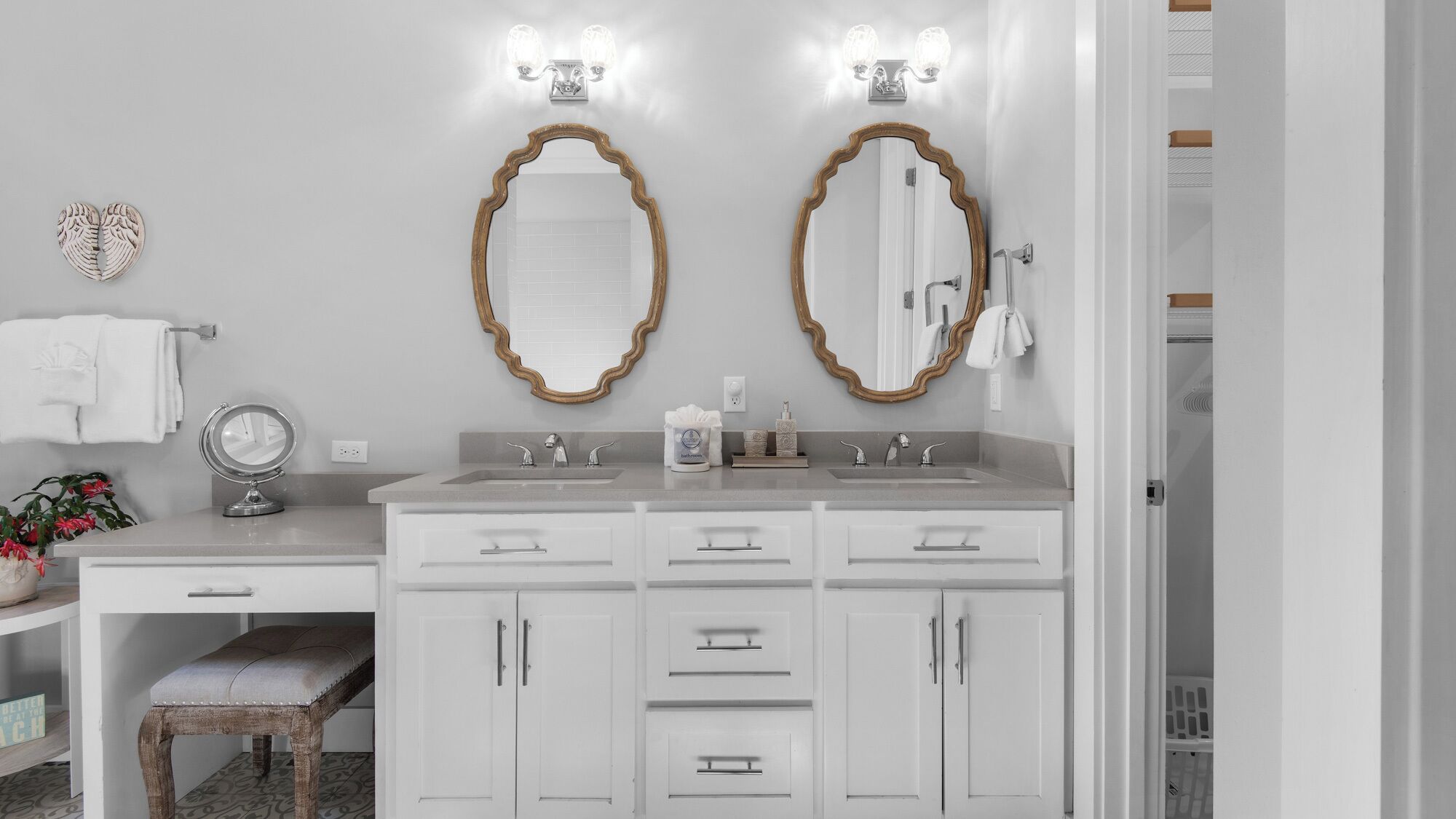Une salle de bain avec deux lavabos, un meuble-lavabo avec des tiroirs, un miroir avec éclairage intégré et un porte-serviettes.