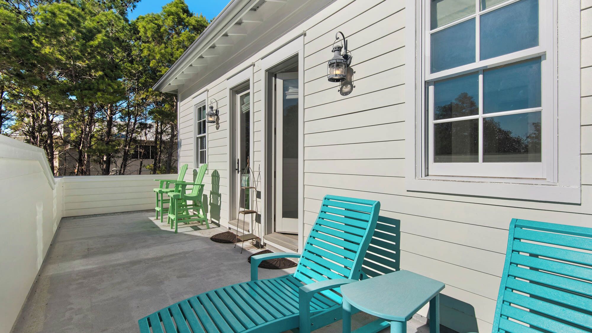A house with a porch, green chairs, a turquoise bench, and a table.