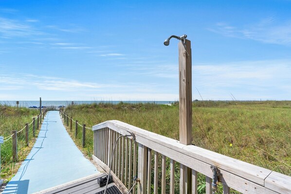 A wooden boardwalk leading to a beach with a clear sky.