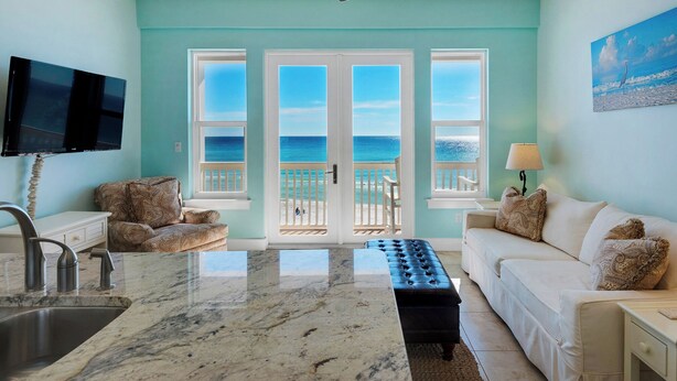 A room with a kitchen area, a dining table, and a sofa. There are three doors leading to a balcony with a view of the ocean. - Gulf Front in Seagrove ~ Amazing Views (Santa Rosa Beach)