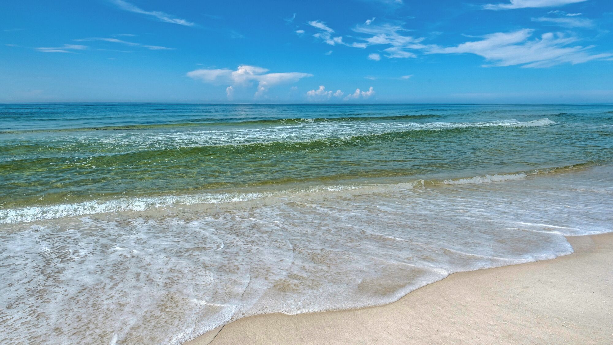 A beach with clear water and a sandy shore.