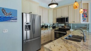 A modern kitchen with stainless steel appliances, a marble countertop, and light-colored cabinetry. - Gulf Front in Seagrove ~ Amazing Views (Santa Rosa Beach)