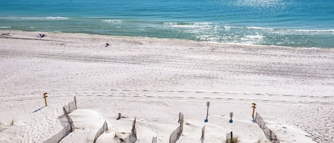 Une plage de sable avec une clôture au premier plan et une vue dégagée sur l’océan.