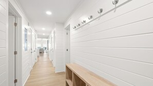A hallway with white walls and wooden flooring, leading to a kitchen area. - Gulf Front in Seagrove Beach With Sweeping Views (Santa Rosa Beach)