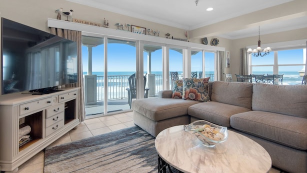 A spacious living room with a large flat-screen TV, a comfortable sofa, a marble coffee table, and a view of the ocean through large sliding glass doors. - Gulf Front in the Heart of Seagrove ~ Sweeping Views ~ Pool ~ Sleeps 8 (Santa Rosa Beach)