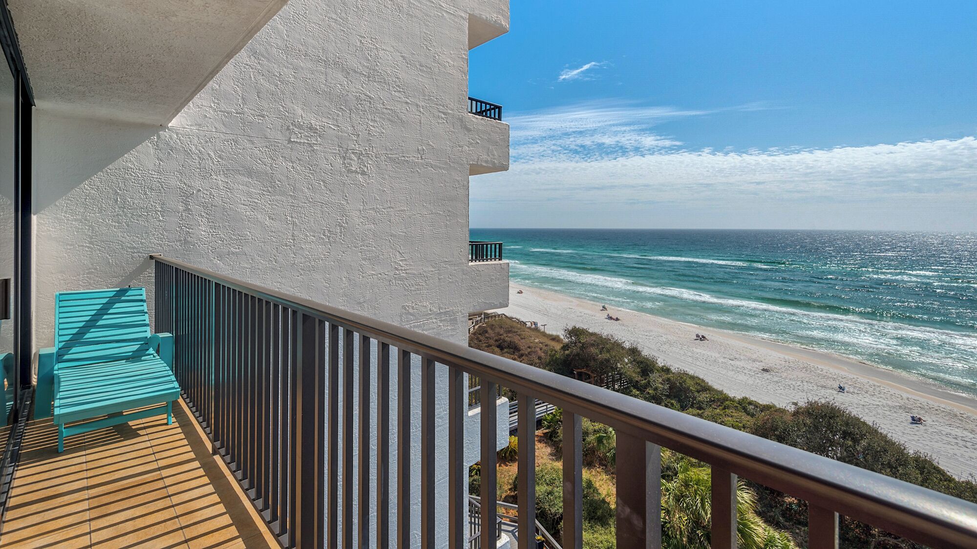 A balcony with a view of the beach and ocean.