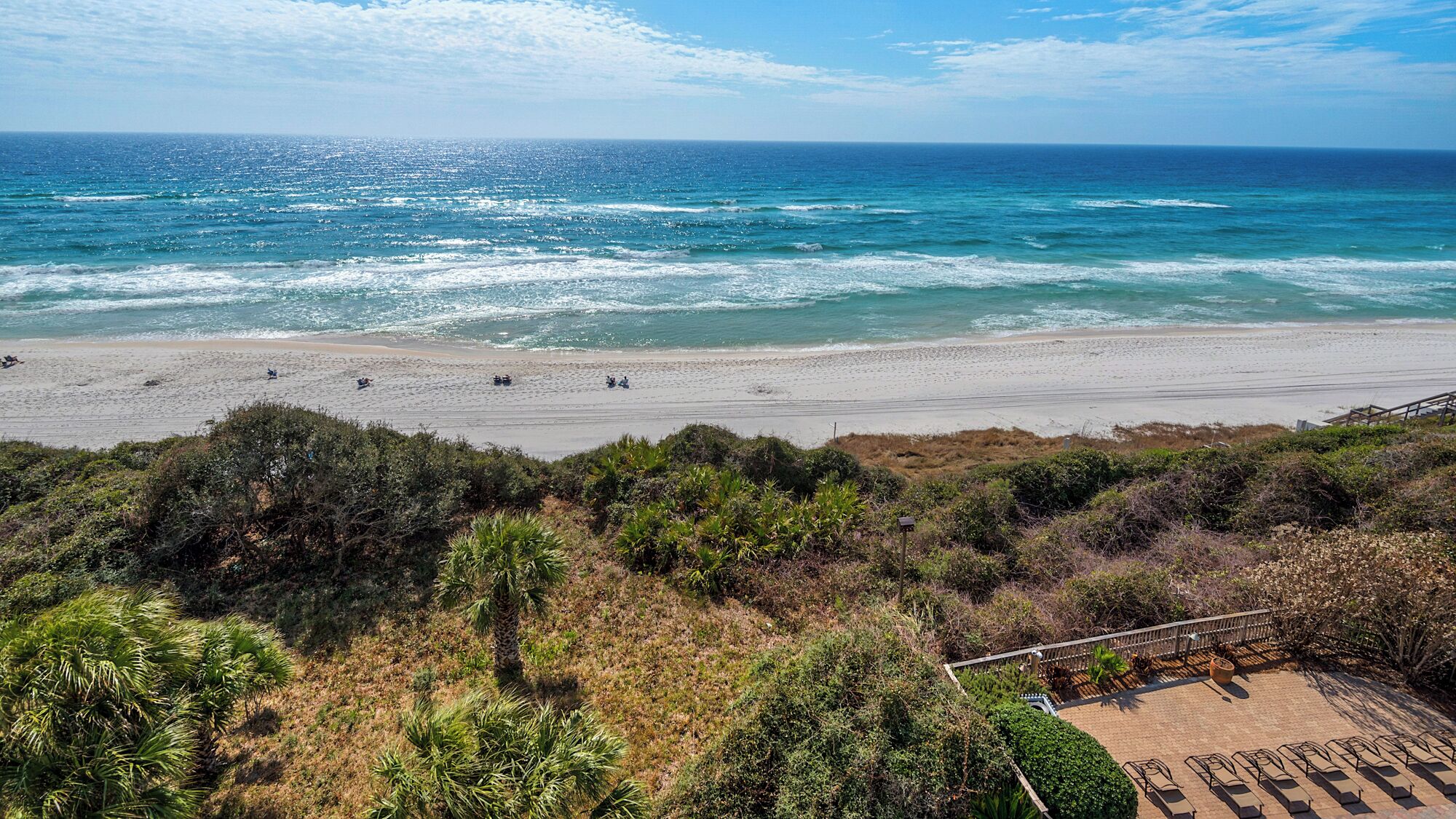 A beach with a sandy shore, a few people, and a view of the ocean.