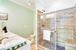 Ein Badezimmer mit einer Duschkabine, einem Waschbecken mit grüner Dekoration und einer Toilette.