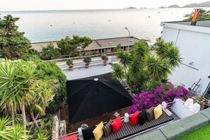 Una terraza en la azotea con una sombrilla negra, zona de estar y vistas al mar.