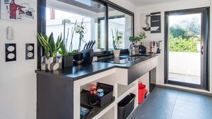 A modern kitchen with a large mirror, built-in appliances, and a view of greenery outside.
