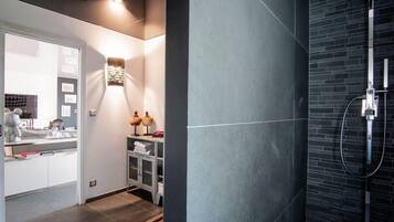 Een moderne badkamer met een douche, een wastafel met spiegel en een klein zitgedeelte.