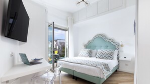 Une chambre avec un lit, un bureau avec un ordinateur portable et une vue sur l’extérieur.