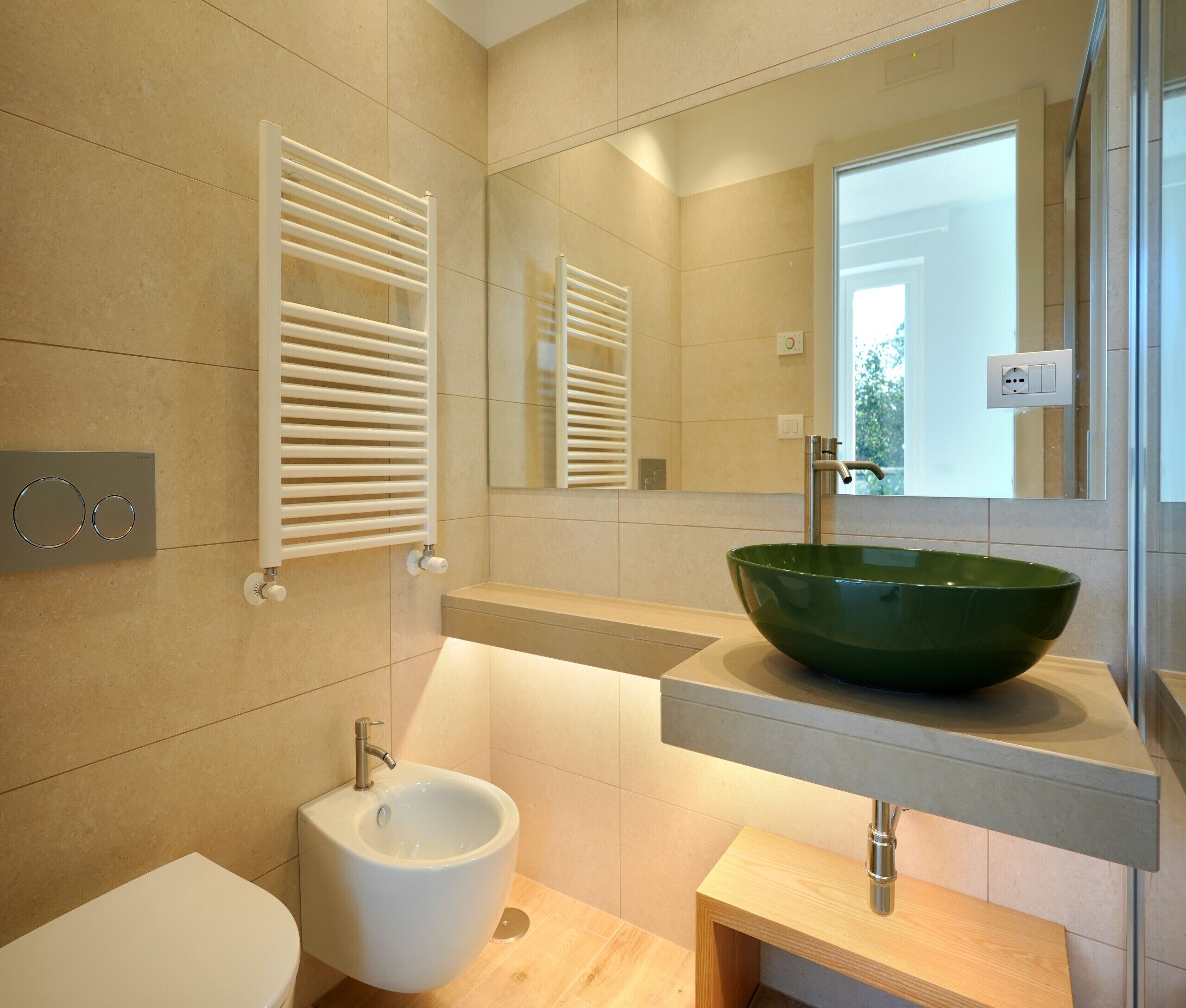 Une salle de bain moderne avec un lavabo sur colonne de couleur verte, un bidet, un porte-serviettes et un miroir.